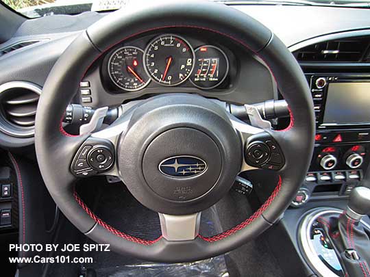 2017 Subaru BRZ Limited gray leather wrapped steering wheel with red stitching, and left side fingertip audio and bluetooth controls, and right side fingertip performance gauge settings. Automatic transmission model shown with steering wheel paddle shifters.