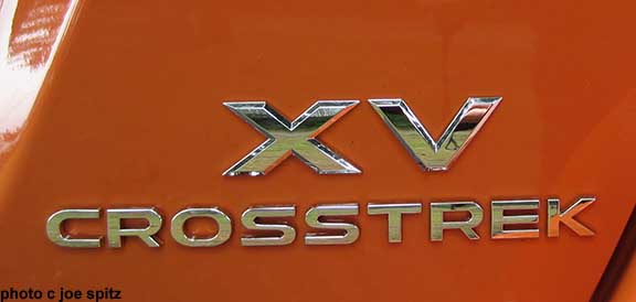2015 XV Crosstrek logo on the rear gate left side. Tangerine orange color shown.