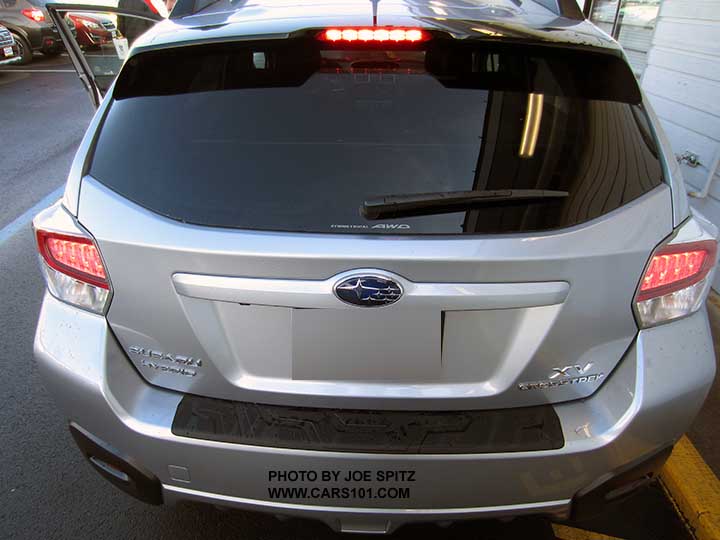 2015 Subaru XV Crosstrek Hybrid rear view showing rear spoiler and LED brake lights, , with optional rear bumper cover step pad, ice silver shown