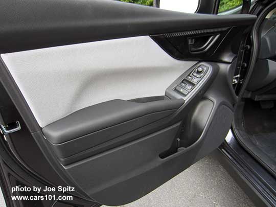 2018 Subaru Crosstrek driver's door panel, 2.0i and Premium model with gray cloth insert, black door handle, matte carbon fiber patterned plastic trim, black tipped power window switches