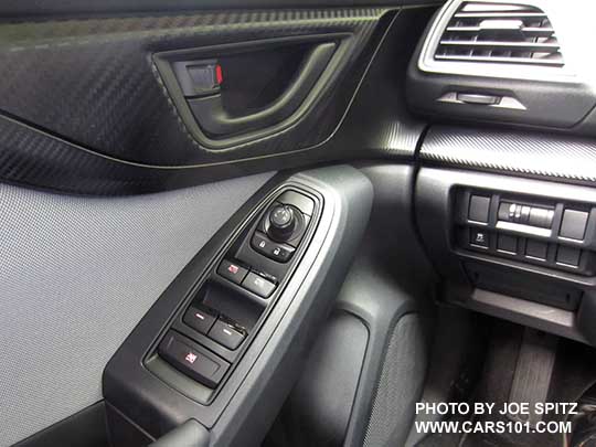 2018 Subaru Crosstrek driver's door panel, 2.0i and Premium model with gray cloth insert, black door handle, matte carbon fiber patterned plastic trim, black tipped power window switches