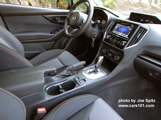 2018 Subaru Crosstrek Premium CVT, silver shift plate, dark carbon fiber-like dash trim, black cloth seats with orange stitching.