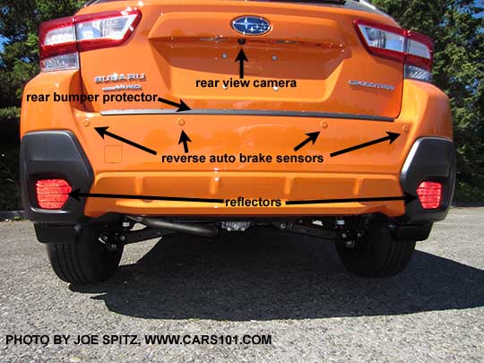 diagrammed 2018 Subaru Crosstrek rear view showing the rear view camera, reflectors, optional rear bumper cover,  Reverse Auto Brake sensors. Sunshine orange shown..