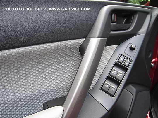 closeup of the 2018 and 2017 Forester front driver's inner door panel with platinum gray cloth door insert and armrest.