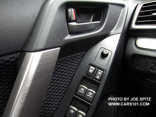 closeup of the 2017 Subaru Forester driver door panel with black door handle, silver tipped power window/lock switches