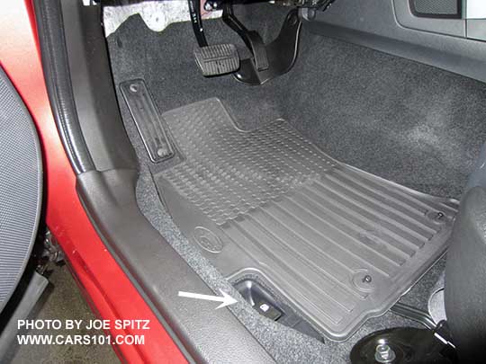closeup of the 2017 Subaru Forester optional All Weather rubber floor mats, driver's mat shown. White arrow points at the fuel door opener.