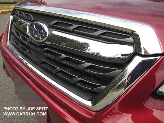 2018 and 2017 Subaru Forester 2.5i, Premium and Limited front grill with chrome center strip and Subaru logo. Venetian red car shown.