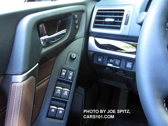 2018 and 2017 Subaru Forester Touring front door panel controls. Saddle brown leather shown, gloss black dash trim, chrome tipper power window buttons, driver seat memory buttons