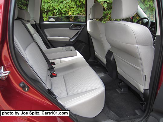 2018 and 2017 Subaru Forester Premium platinum gray cloth rear seat with armrest with cupholders. Venetian red car shown.