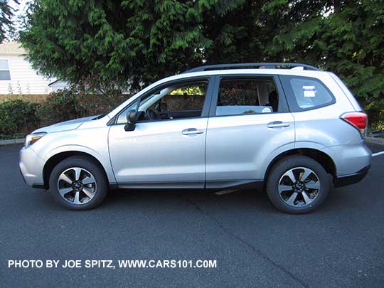 2017 Subaru Forester 2.5 base model with black unpainted outside mirrors, lightly tinted rear glass (no dark tint) and no rear spoiler. Shown with optional Alloy Wheel/Roof Rail Package, ice silver.