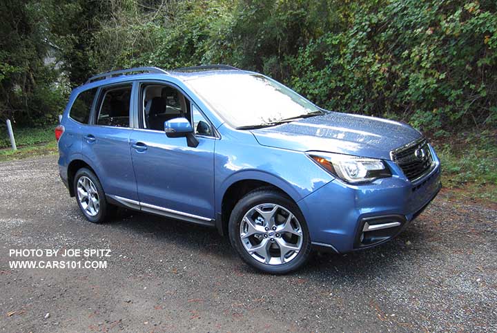 2018 and 2017 Quartz Blue Subaru Forester Touring model. 2.5i shown with 18" brushed silver wheels.