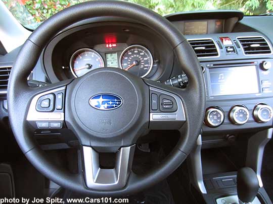 2018 and 2017 Subaru Forester 2.5i vinyl coated steering wheel with audio, bluetooth and cruise control. The 6.2" audio with physical buttons in the background indicates this is a 2.5i base model.