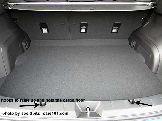 2017 Subaru 2017 Subaru Impreza 5 door hatchback cargo area, with black arrows pointing at the hooks to slightly raise the cargo floor for easier loading.  Note the child seat tethers on the rear seatbacks