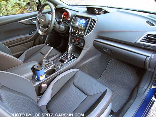 2017 Subaru Impreza Sport black cloth interior from passenger side. Gloss black CVT shift knob and surround, 8" audio screen, heated seat buttons, dual fixed cupholders (with blue cup), all weather floor mats.