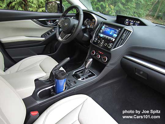 2017 Subaru Impreza Limited leather front seats, CVT gloss black shift knob and surround, 8" audio, silver trimmed automatic climate control knobs, heated seat buttons, two fixed cupholders (with blue travel mug shown). ivory leather shown from passenger side