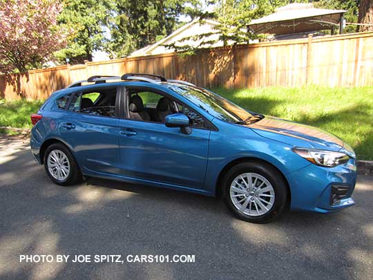 side view 2017 Subaru Impreza 5 door hatchback. Island blue pearl color. with 16" silver alloys, silver roof rack rails, body color door handles and mirrors. Optional roof rack aero crossbars.