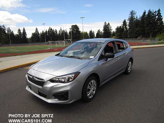 front view 2017 Subaru Impreza 2.0i base model 5 door hatchback, ice silver shown. Steel wheels with covers, no fog lights,  unpainted mirrors, no roof rails.