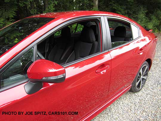 closeup of the 2017 Subaru Impreza Sport 4 door sedan, body colored turn signal outside mirrors, black lower window trim, body colored door handles, black cloth interior, 18" machined alloys. lithium red pearl shown