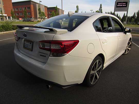 2017 Subaru Impreza Sport 4 door sedan with gloss back rear spoiler with body colored ends, machined 18" alloys, body colored mirrors with turn signals, black lower window trim. Crystal white shown