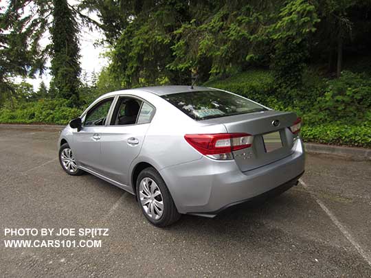 rear view 2017 Subaru Impreza 2.0i 4 door sedan, with black outside mirrors, 16" wheels with plastic wheel covers. Ice silver shown.