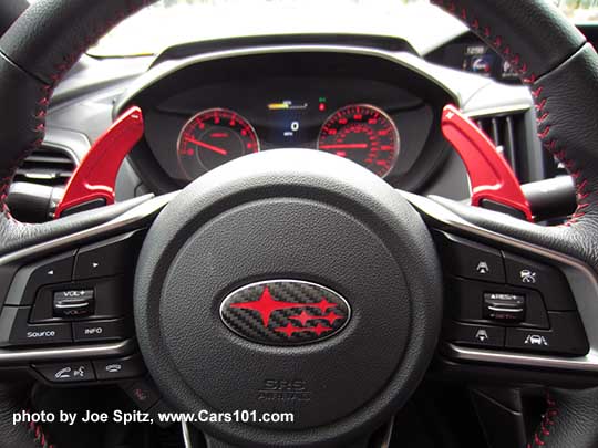 closeup of a 2017 Subaru Impreza Sport steering wheel with aftermarket, larger paddle shifters, and red center Subaru Pleiades logo