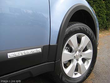 closeup of optional wheel arch moldings on 2011 Outback, sky blue