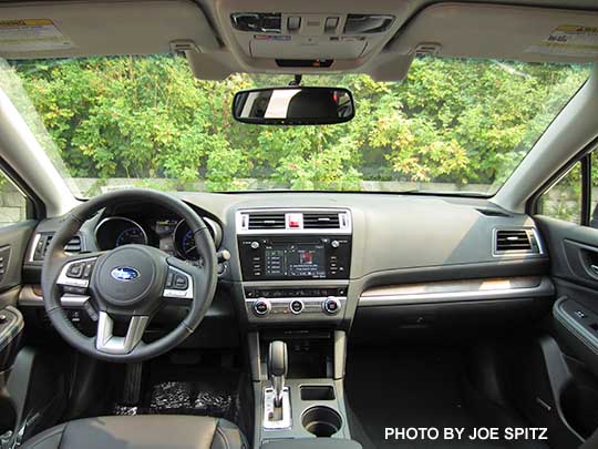 2016 Subaru Outback 2.5i Limited interior with wood dash trim, off black leather shown,. Optional eyesight cameras by the rear view mirror.