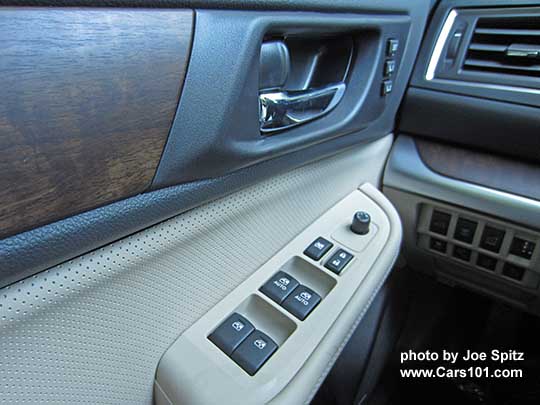 closeup of the 2017 Subaru Outback Limited driver's door woodgrained door and dash trim, warm ivory perforated leatherette insert, chrome inner handle, power window buttons, memory seat buttons