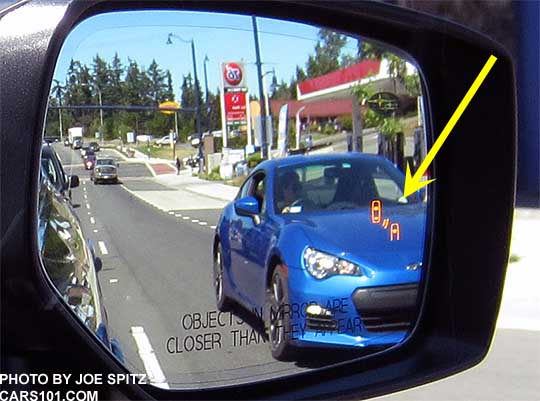 2017 Subaru Outback right outside mirror with blind spot detection, passenger side shown, with WR Blue BRZ approaching in the lane