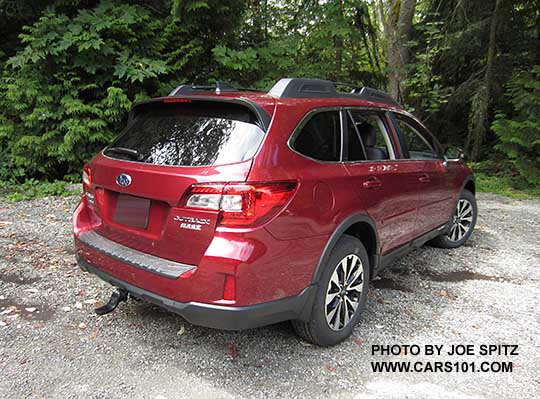 rear view  2017 Subaru Outback Limited, 18" machined black and silver wheels. Venetian red shown with optional trailer hitch, rear bumpoer cover, splash guards