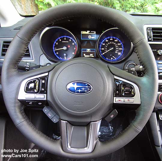 2017 Outback Touring heated, gray leather wrapped steering wheel with gloss black and silver fingertip buttons, and a thin chrome trim strip around the lower center spoke