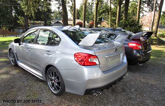 rear view, two 2015 STIs side by side, ice silver and dark gray
