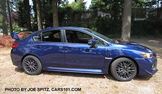 Subaru 2016 WRX STI has 18" gray alloys, black inner headlight surrounds, tall rear spoiler, lapis blue color