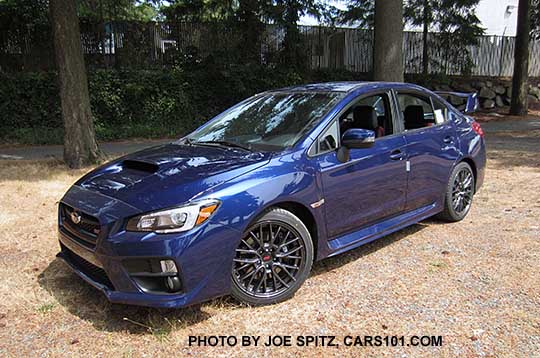 2016 WRX STI has black inner headlight surrounds, gray alloys, tall rear spoiler. New for 2016 WRX, STI Lapis Blue shown