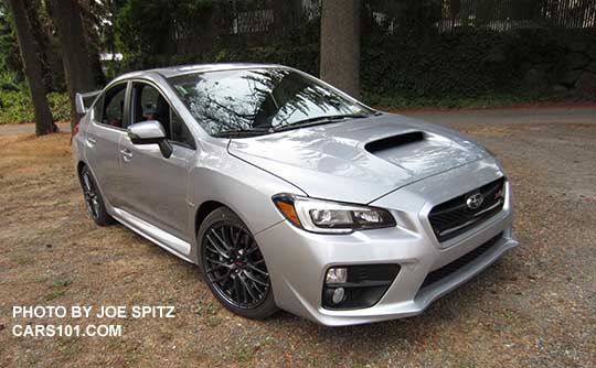 front quarter view, ice silver  2016 WRX STI with standard black inner headlight surrounds, 18" gray multi-spoke alloys, fog lights...