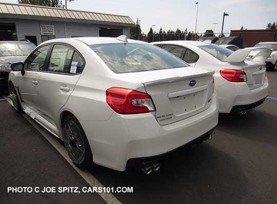 next to each other- two white 2016 WRX STIs.  Limited STI with small trunk lip spoiler and STI with tall wing spoiler