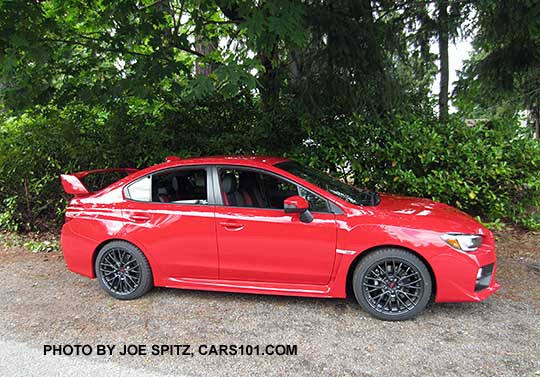 2017 Subaru STI with tall wing spoiler, black alloys. Pure red color