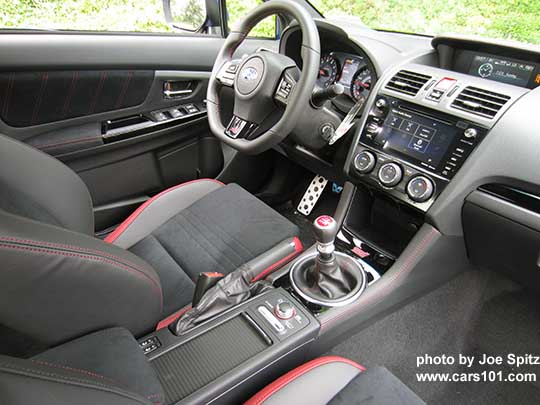 2018 Subaru WRX STI interior- black and red seats, center console heated seat buttons, sliding cupholder cover (shown closed),  DCCD,  SI Drive, gloss black trim with STI storage illuminated red logo